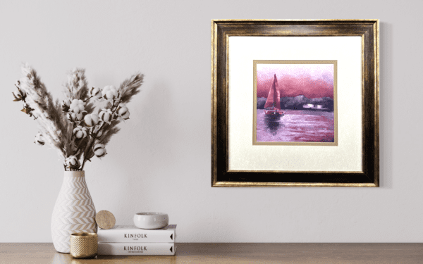 A lone sailboat with a striking muted red sail, glides through calm waters, set against a dramatic pink and purple sky. The tranquil scene invites viewers to embrace a moment of peace, capturing the beauty of a solitary journey on the open water.